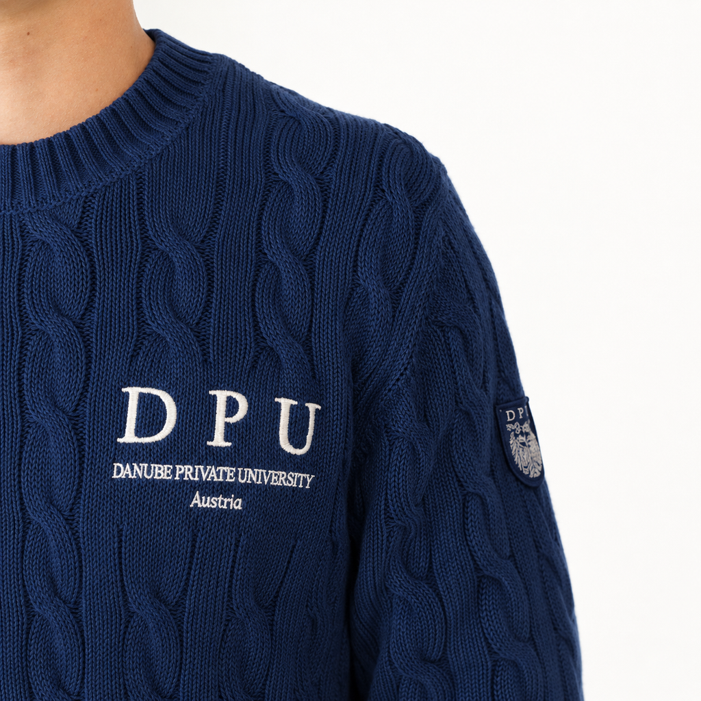 DPU Strickpullover in dunkelblau mit klassischem Zopfmuster, winterweißem DPU-Stick und aufgenähtem Wappen-Patch am Ärmel.
