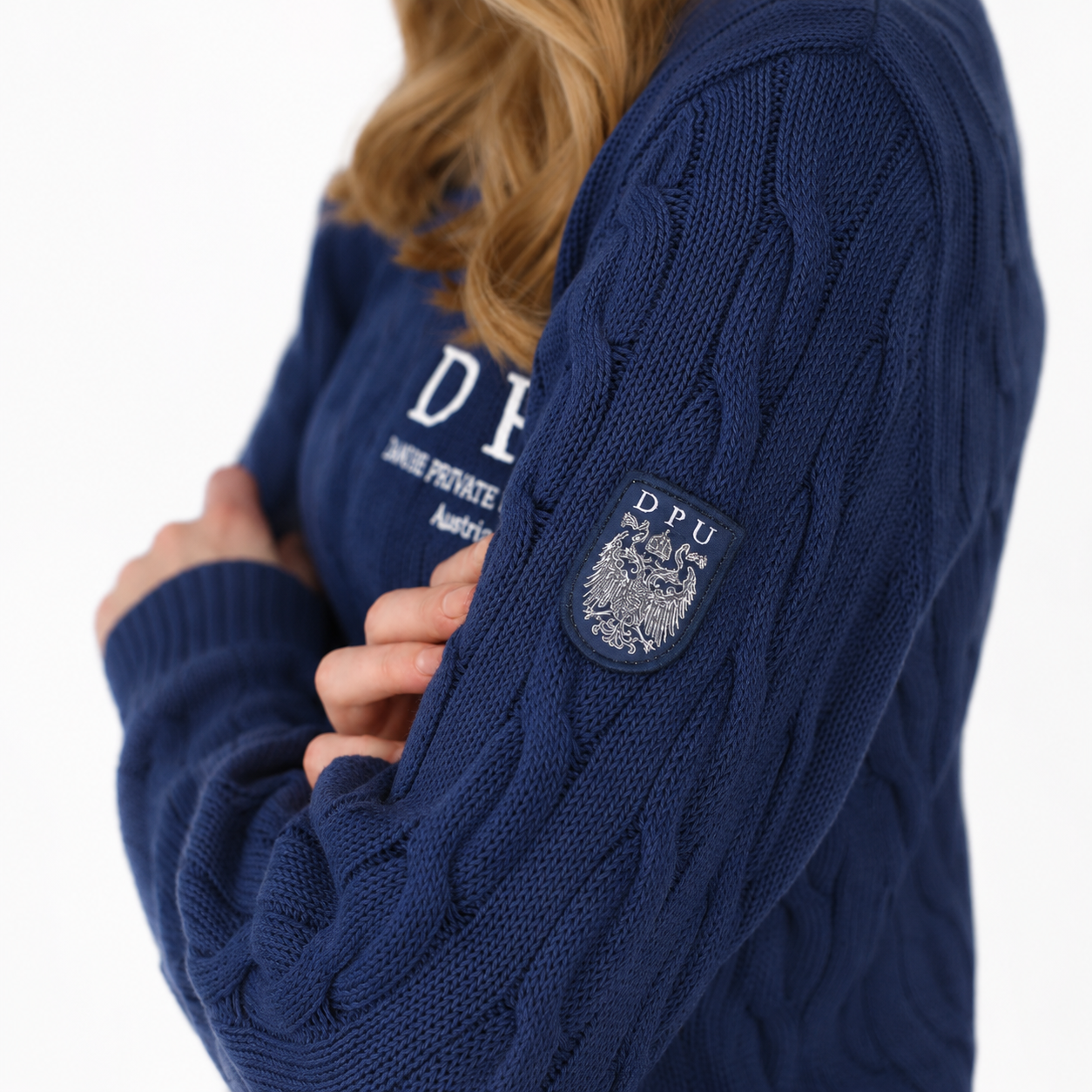 DPU Strickpullover in dunkelblau mit klassischem Zopfmuster, winterweißem DPU-Stick und aufgenähtem Wappen-Patch am Ärmel.