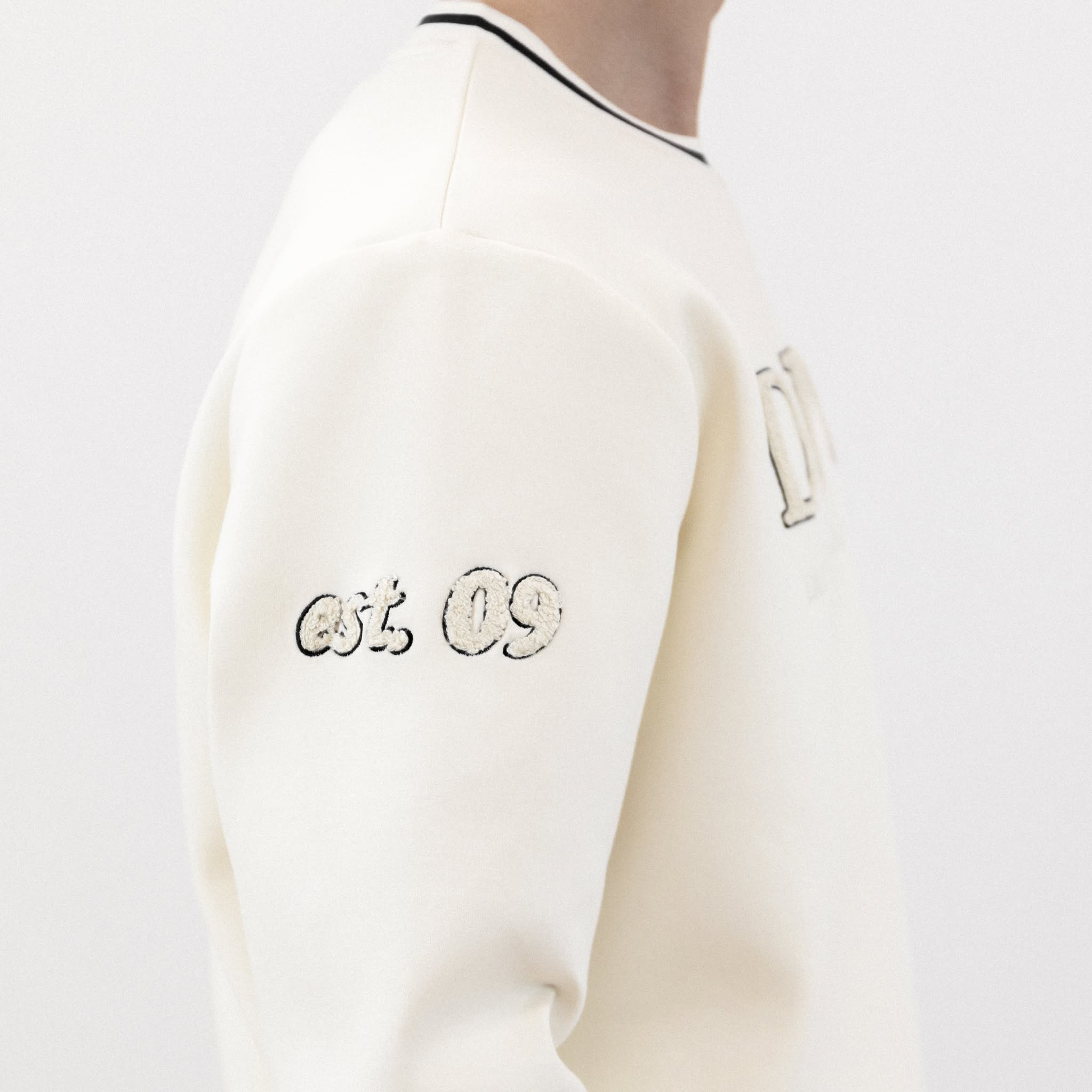 Detailaufnahme vom Ärmel des Winterweißen DPU-Sweatshirt mit est. 09 am rechten Ärmel.